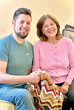 Tony Burkhart and his mother Janine Schorsch hold a prayer blanket that was made by the Ladies Sodality Prayer Shawl Ministry of All Saints Parish in Dearborn County. When Burkhart was at the edge of death in a hospital, Schorsch rushed to bring the blanket to him, wanting her son to be wrapped in prayers and God’s grace. (Submitted photo)
