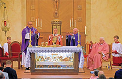 Father Douglas Hunter, left, Archbishop Charles C. Thompson, Father Nicholas Dant and Father James Wilmoth extend their hands during the eucharistic prayer of a special Mass on Dec. 11 at St. Roch Church in Indianapolis marking the parish’s 100th anniversary of its founding. Kneeling in back are altar servers Ezekiel Littell, left, and Isaiah Littell, far right. (Photo by Natalie Hoefer)