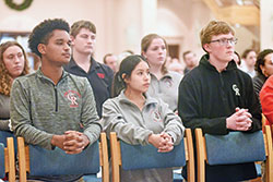 Yosef Estifanos, left, Jennifer Cazares and Charles Hutt, all students at Cardinal Ritter Jr./Sr. High School in Indianapolis, kneel in prayer on Jan. 5 during a Mass at SS. Peter and Paul Cathedral in Indianapolis. (Photo by Sean Gallagher)