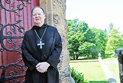 Benedictine Archabbot Kurt Stasiak stands on June 6, 2016, next to the Archabbey Church of Our Lady of Einsiedeln in St. Meinrad. He and the Benedictine monks of Saint Meinrad Archabbey found special meaning in the ministry of the late Pope Benedict XVI, who honored the founder of their order in his choice of his papal name. (File photo by Sean Gallagher)