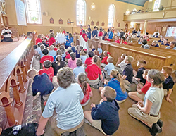 Students of St. Nicholas School in Ripley County gather with Father Shaun Whittington around a monstrance during a holy hour of adoration on Sept. 28, 2021, in St. Nicholas Church. (Submitted photo)
