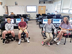 Eli Pac, left, Thomas Nguyen, Tessa Mize and Lauren Koleszar, all eighth-graders at St. Barnabas School in Indianapolis, sit in their school’s computer classroom. They worked to develop a website and app that will help Hakha Chin Catholics in Indianapolis, Myanmar and around the world to pray and grow in their faith. (Submitted photo)