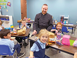 Father Kyle Rodden shows his delight in sharing time and joy with some children at St. Joseph Catholic School in Corydon, where he makes it his mission to bring students closer to God and the Catholic faith. (Submitted photo)