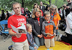 Sebastian, left, Ella, Angie and Benjamin Moster, members of St. Louis Parish in Batesville, kneel in prayer on Sept. 27, 2015, beside the Benjamin Franklin Parkway in Philadelphia during the closing Mass of the eighth World of Meeting of Families. The Together in Holiness conference on April 22 at St. Jude Parish in Indianapolis and the following seven-week formation series are meant to help build the domestic Church in the archdiocese. (File photo by Sean Gallagher)