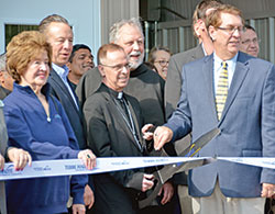 Patricia Etling, left, Terre Haute mayor Duke Bennett (behind Patricia), Archbishop Charles C. Thompson and Catholic Charities Terre Haute agency director John C. Etling cut a ribbon for the opening of Catholic Charities Terre Haute’s newly constructed foodbank during a ceremony on April 29, 2019, in Terre Haute. (File photo by Natalie Hoefer)