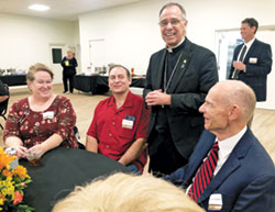 Lyn Carter, left, and her husband Philip Carter, members of St. Francis Xavier Parish in Henryville, left, and Charles Ledbetter, a member of St. Michael Parish in Charlestown, smile with Archbishop Charles C. Thompson during a United Catholic Appeal dinner on Oct. 5 at St. Augustine Parish in Jeffersonville. (Photo by Leslie Lynch)