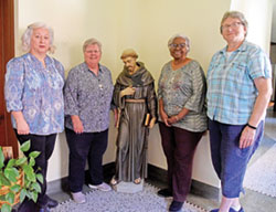 Maureen Pisani, left, Franciscan Sister Kathleen Branham, Franciscan Sister Janette Marie Pruitt and Franciscan Sister Susan Marie Pliess pose by a statue of St. Francis of Assisi on Oct. 4, the feast of St. Francis, on the grounds of the Oldenburg Franciscan sisters in Oldenburg. Pisani is a postulant for the religious community. (Photo by Sean Gallagher)