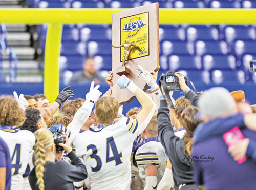 Members of the football team of Our Lady of Providence High School in Clarksville raise Indiana’s Class 1A state championship trophy in joy after completing a perfect 14-0 season when they defeated the team from North Judson High School 35-20 on Nov. 30. (Submitted photo)