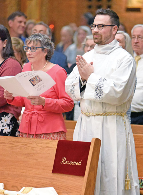 Seminarian Liam Hosty holds his hands in prayer during an April 27, 2024, Mass at St. Barnabas Church in Indianapolis in which he was ordained a transitional deacon. Pictured at left is his mother, Julie Hosty. Deacon Hosty will be ordained a priest at 10 a.m. on June 7 at SS. Peter and Paul Cathedral in Indianapolis. (Photo by Sean Gallagher)