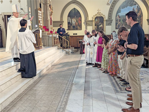 Seminarian Liam Hosty holds his hands in prayer during an April 27, 2024, Mass at St. Barnabas Church in Indianapolis in which he was ordained a transitional deacon. Pictured at left is his mother, Julie Hosty. Deacon Hosty will be ordained a priest at 10 a.m. on June 7 at SS. Peter and Paul Cathedral in Indianapolis. (Photo by Sean Gallagher)