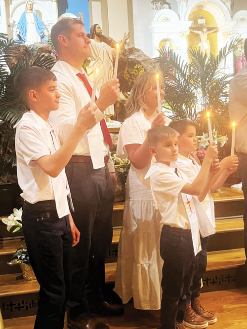 The May family, featured in an article starting on page 1, hold candles after being baptized on April 19 during the Easter Vigil Mass in St. Martin Church in Yorkville, one of four churches of All Saints Parish in Dearborn County. The family members are David, left, Cole, Christina, Harrison and Maxwell. (Submitted photo)