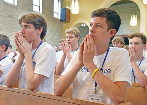 Conrad Otten, a member of St. John Vianney Parish in Fishers, Ind., in the Lafayette Diocese, left, and Matthew Biehl, front row, a member of St. Gabriel Parish in Connersville, kneel in prayer on July 8 during a Mass in the chapel of Bishop Simon Bruté College Seminary in Indianapolis during the archdiocese’s annual Bishop Bruté Days vocations camp. Also taking part in the camp are Joshua Fuller, second from left, of Our Lady of the Greenwood Parish in Greenwood, and Joshua Skidmore, right, a member of Our Lady of the Most Holy Rosary Parish in Indianapolis. (Photos by Sean Gallagher)