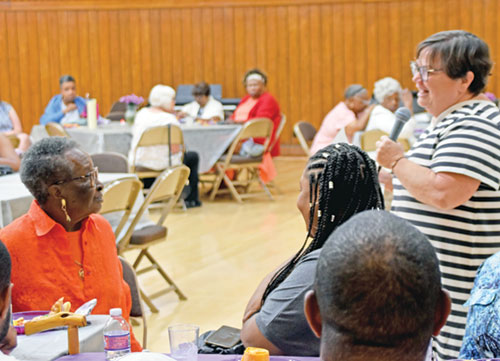 At a Senior Companion Program (SCP) volunteer gathering at the Archbishop Edward T. O’Meara Catholic Center in Indianapolis on Aug. 6, Joyce Beaven, senior services director for Catholic Charities Indianapolis, right, offers words of gratitude to Alice Whitney, left, 94, for her 25 years volunteering with SCP. (Photo by Natalie Hoefer)