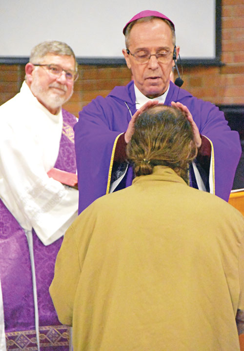 Archbishop Charles C. Thompson, principal celebrant of a Mass at the Plainfield Correctional Facility in Plainfield on March 26, 2023, offers a blessing to a man who was soon to be released from the facility. Deacon Martin “Neil” May smiles at left. (File photo by Natalie Hoefer)