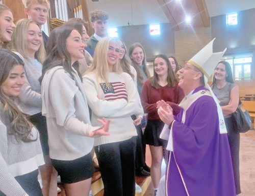 Archbishop Charles C. Thompson shares a moment of joy with students from Brebeuf Jesuit Preparatory School in Indianapolis following the Mass he celebrated for high school seniors from across the archdiocese on Dec. 10, 2025, at St. Malachy Church in Brownsburg. (Photo by John Shaughnessy)