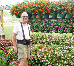 Bill Larkin stands in front of a display of flowers and birdhouses at his home in rural Daviess County. (Message photo by Mary Ann Hughes)