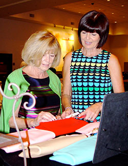 Linda Feulner and Karen Hinderliter examine purses before guests arrive for the third annual Haiti Purse Party. Both are members of the committee which raises funds for St. James Parish in Plaine du Nord, Haiti, a parish which has been adopted by St. Joseph Parish in Vanderburgh County. (Message photo by Mary Ann Hughes)