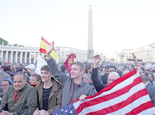 Men holding a U.S. flag cheer as Cardinal Robert Francis Prevost, who has chosen the papal name Leo XIV, appears on the central balcony of St. Peter's Basilica at the Vatican May 8, 2025, following his election during the conclave. He is the first American pope in history. (OSV News photo/Amanda Perobelli, Reuters)