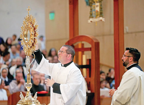 Father Eric Augenstein, archdiocesan director of seminarians, places a host in a monstrance during a Mass for the feast of Corpus Christi at the Cathedral of Our Lady of the Angels in Los Angeles on June 22 during the National Eucharistic Pilgrimage. Father Augenstein served as a master of ceremonies at the liturgy. (OSV News photo/Bob Roller)